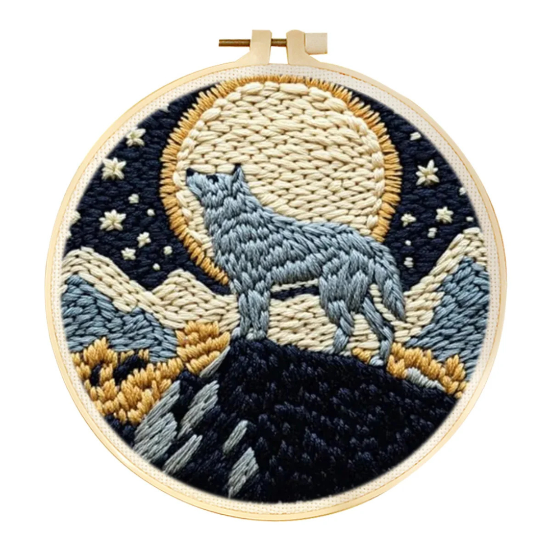 Embroidery hoop with a wolf and moon design against a starry night sky.
