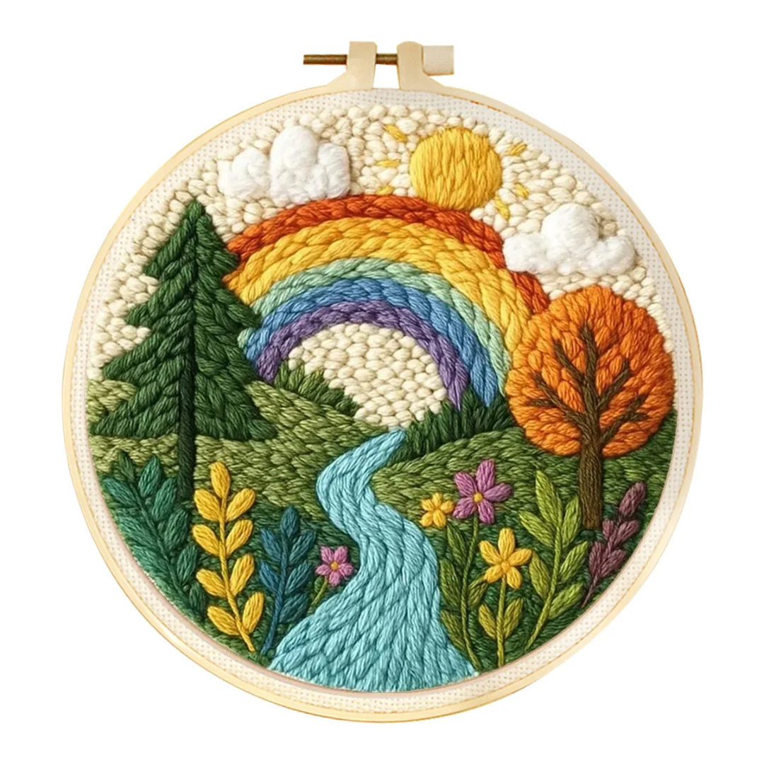 Embroidery hoop with a colorful landscape design featuring trees, flowers, and a rainbow.