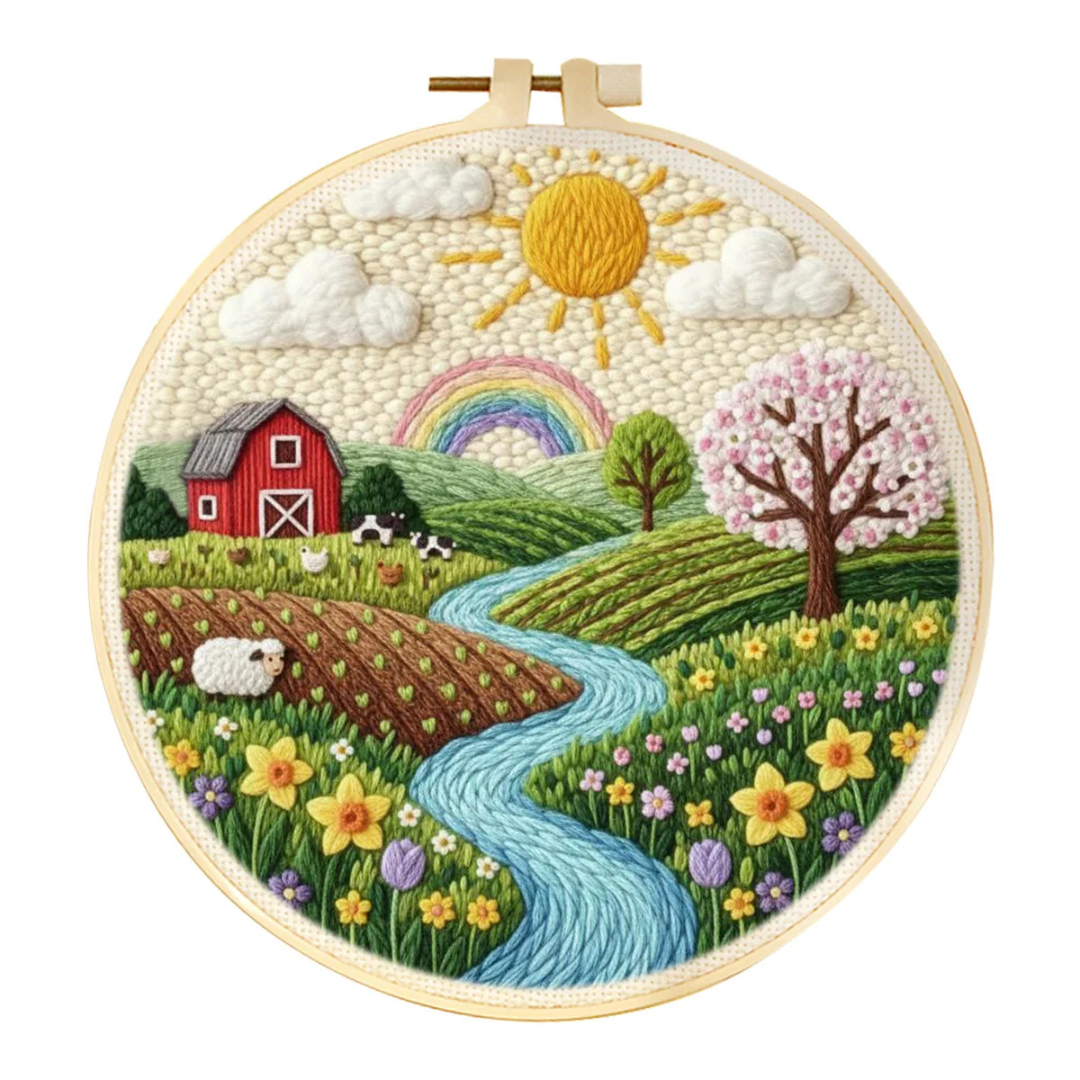 Embroidery hoop with a colorful landscape design featuring a barn, rainbow, and stream.