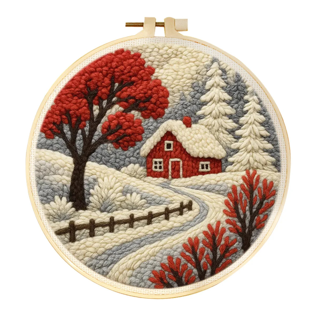 Embroidery hoop with a winter scene featuring a red cabin and trees.