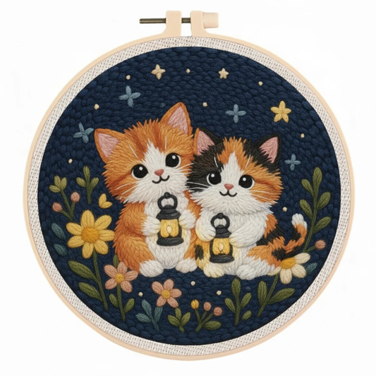 Embroidery hoop with two cats holding lanterns on a dark blue background