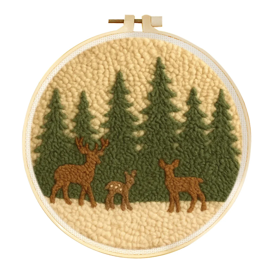 Embroidery hoop with a forest scene featuring deer and trees.