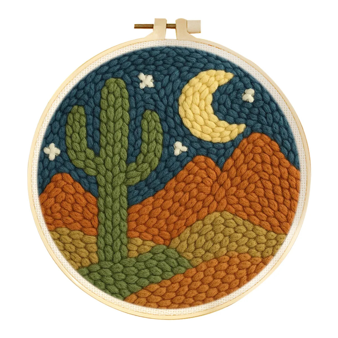 Embroidery hoop with a desert landscape design featuring a cactus, moon, and stars.