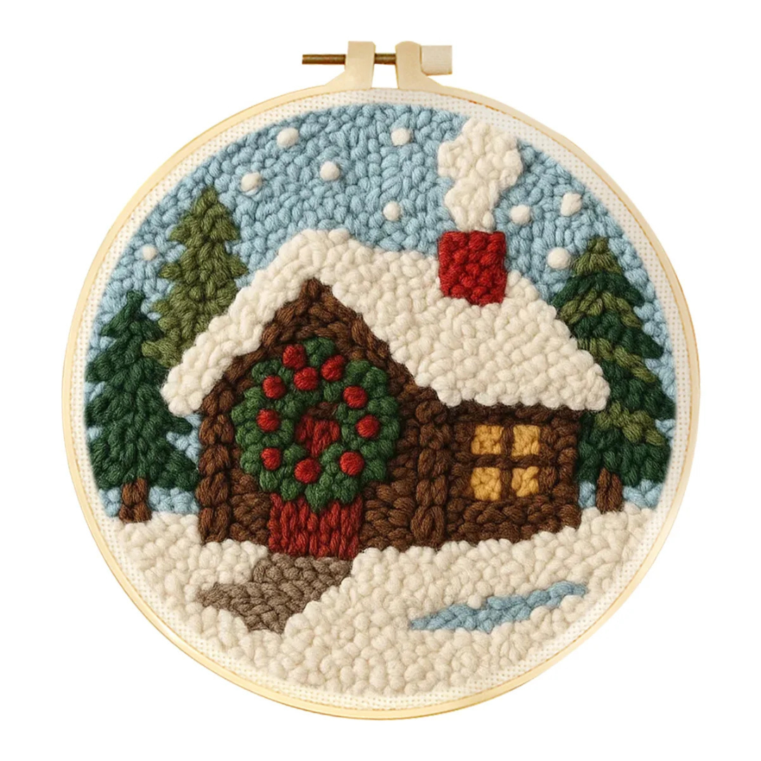 Embroidery hoop with a winter scene of a cabin and trees.