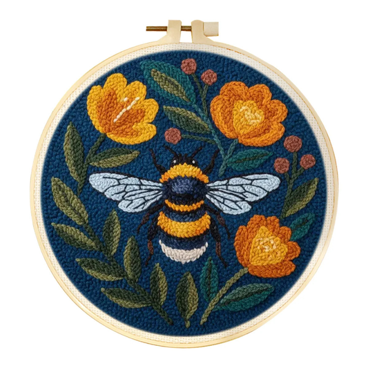 Embroidery hoop with a bee and floral design on a blue background