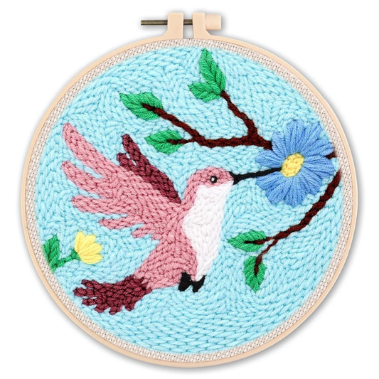 Embroidery hoop with a pink hummingbird and blue flower design on a light blue background.