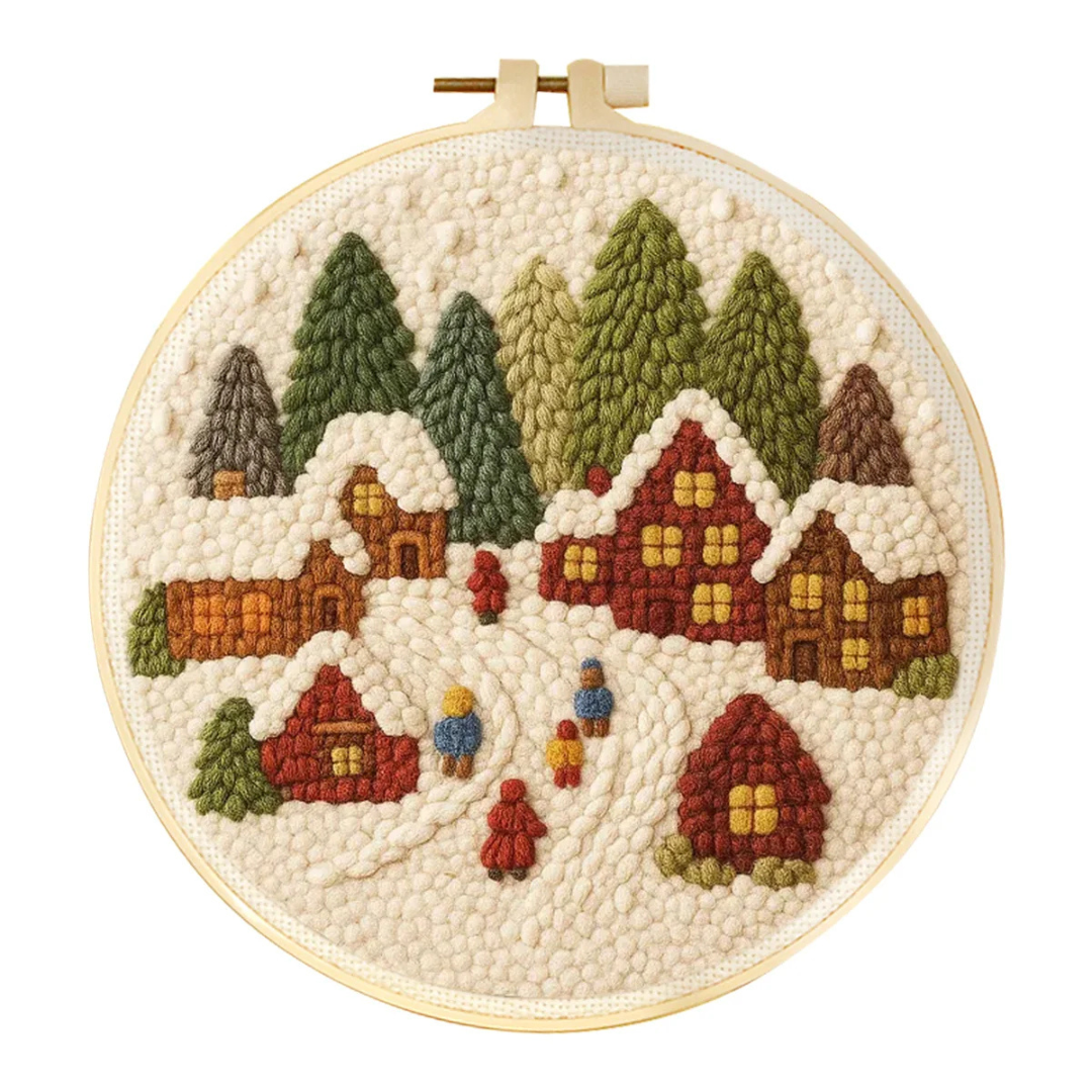 Embroidery hoop with a winter village scene including houses and trees.