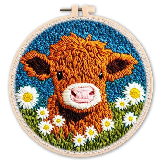 Embroidery hoop with a cow and daisy design on a white background